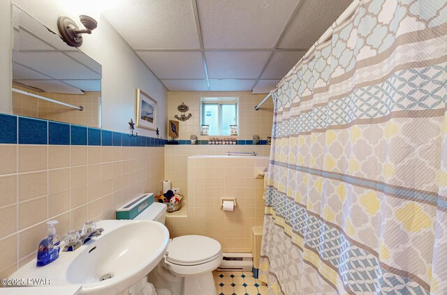 163 Wild Acres Dr, Dingmans Ferry, PA 18328 - bathroom with a baseboard heating unit, a drop ceiling, tile walls, toilet, and a shower with curtain