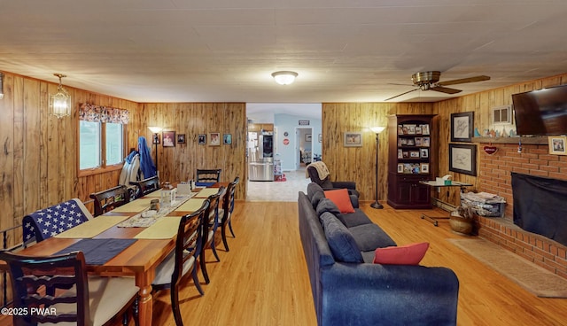 163 Wild Acres Dr, Dingmans Ferry, PA 18328 - living room featuring wood walls, a brick fireplace, wood finished floors, and a ceiling fan