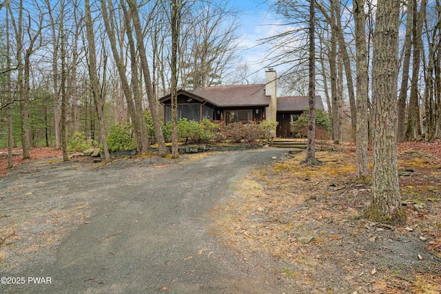 120 Burning Tree Dr, Lords Valley, PA 18428 - view of front of home with asphalt driveway, a chimney, a sunroom, and board and batten siding