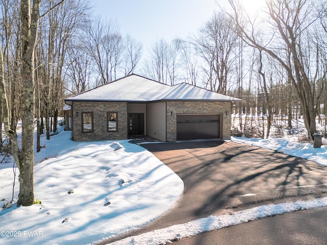 view of front facade with an attached garage, driveway, and stone siding