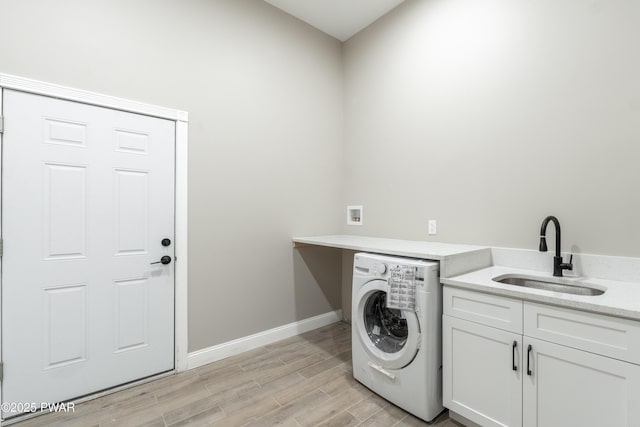 laundry room featuring washer / clothes dryer, light hardwood / wood-style flooring, cabinets, and sink