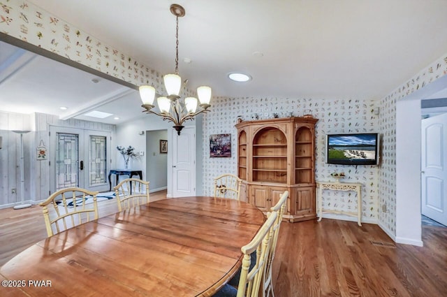 dining space featuring beam ceiling, dark hardwood / wood-style floors, and an inviting chandelier