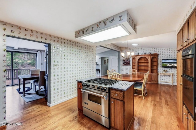 kitchen featuring high end stainless steel range oven, a chandelier, decorative light fixtures, a kitchen island, and light wood-type flooring