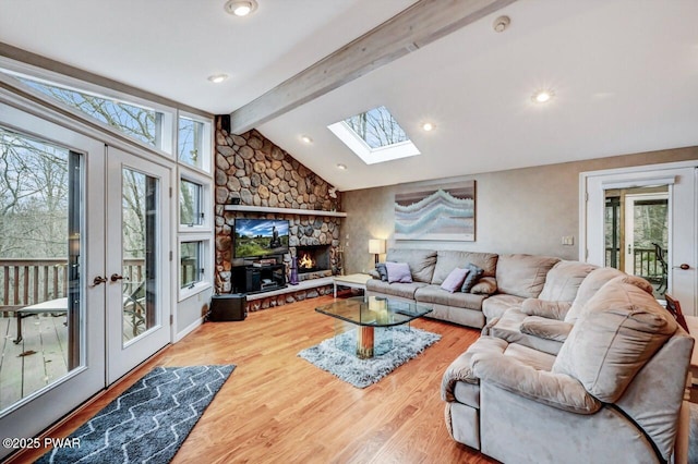 living room with a fireplace, lofted ceiling with skylight, french doors, and hardwood / wood-style floors