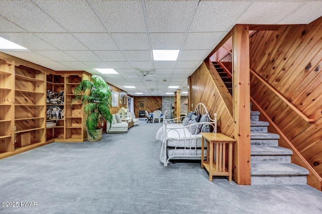 unfurnished room with carpet floors, wooden walls, and a paneled ceiling