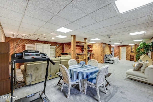 dining space featuring a paneled ceiling, carpet floors, and wooden walls