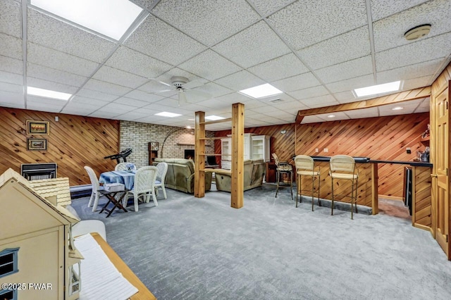 interior space featuring carpet flooring, a paneled ceiling, and wood walls