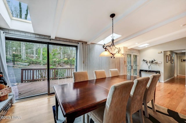 dining room featuring light hardwood / wood-style flooring, a chandelier, and vaulted ceiling with skylight