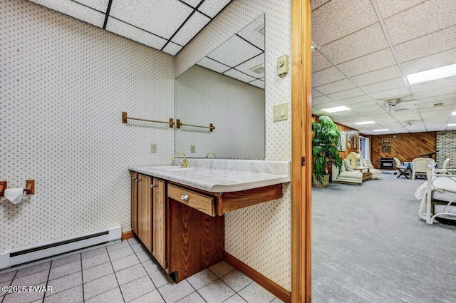 bathroom featuring vanity, a drop ceiling, a baseboard heating unit, and wood walls