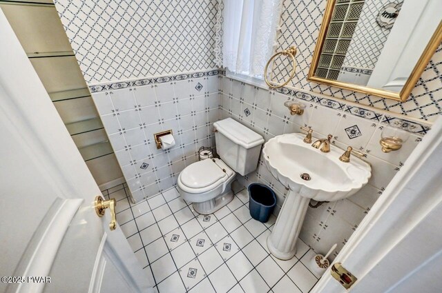 bathroom featuring tile patterned floors, sink, tile walls, and toilet