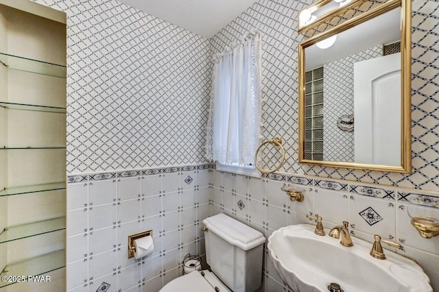 bathroom with toilet, tile walls, and sink