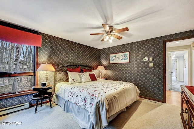 carpeted bedroom featuring ceiling fan and a baseboard heating unit