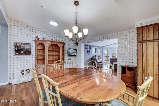 dining room with light wood-type flooring, an inviting chandelier, and vaulted ceiling