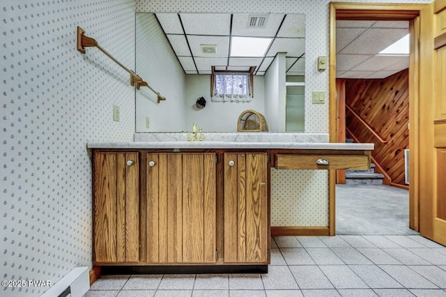 bathroom with a drop ceiling, wood walls, and vanity