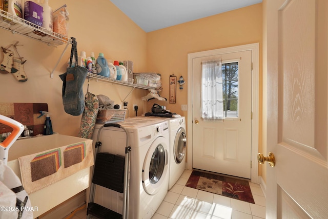 washroom with laundry area, a sink, washing machine and dryer, and light tile patterned flooring
