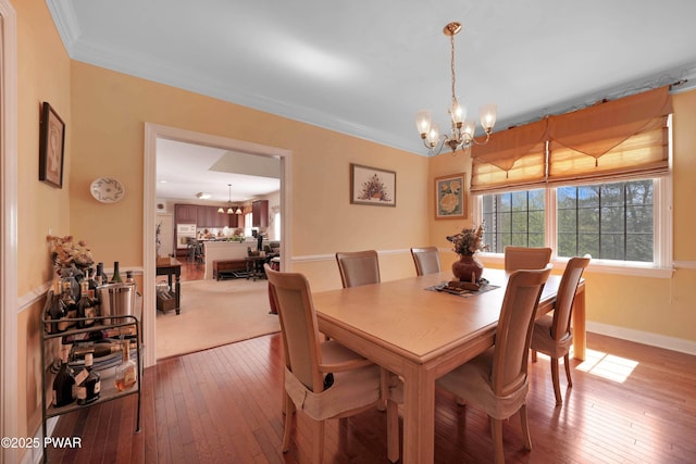 dining space with wood-type flooring, a chandelier, and ornamental molding