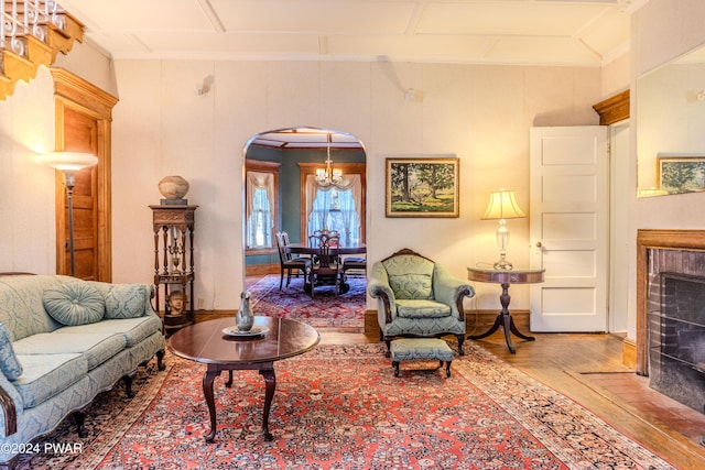 living room with hardwood / wood-style floors, crown molding, and an inviting chandelier