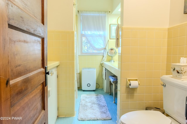 bathroom featuring tile patterned flooring, toilet, and tile walls