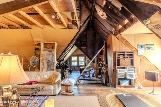 unfurnished living room featuring lofted ceiling with beams, wood walls, wood-type flooring, and wooden ceiling