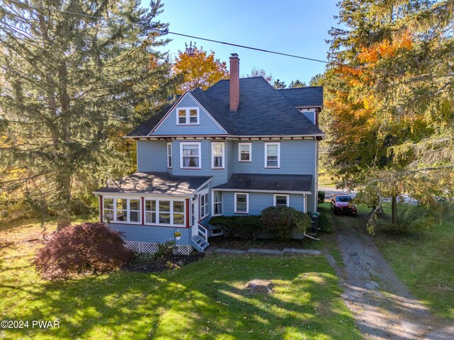 view of front of property featuring a front yard and a sunroom