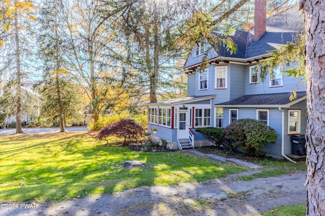 view of front of home with a sunroom and a front yard