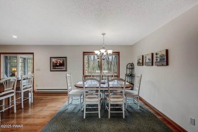 dining space with wood finished floors, baseboards, a textured ceiling, baseboard heating, and a chandelier