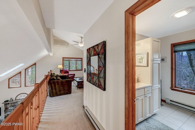 hall with a baseboard heating unit, lofted ceiling, and light carpet