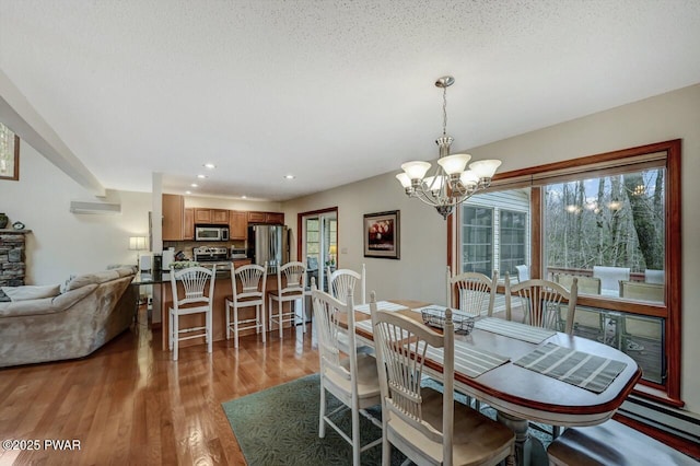 dining area with a chandelier, light wood-type flooring, recessed lighting, a textured ceiling, and a wall mounted AC