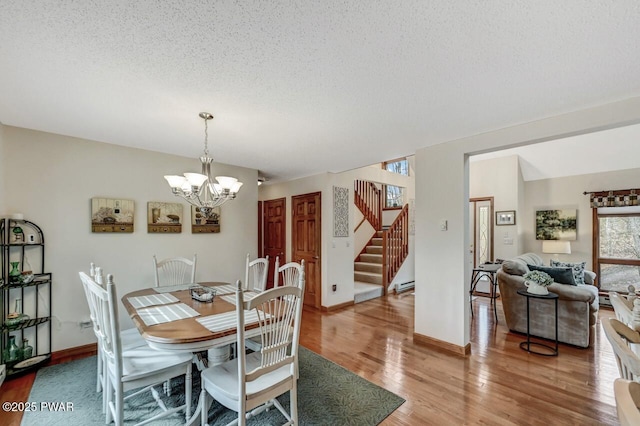 dining space featuring baseboards, light wood finished floors, stairs, a textured ceiling, and a notable chandelier