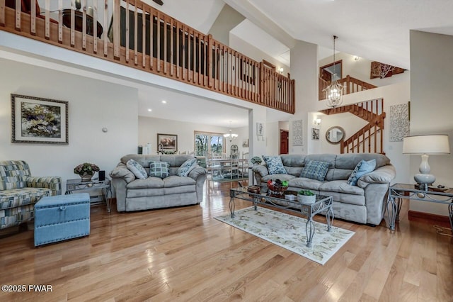 living room featuring stairs, an inviting chandelier, wood finished floors, and high vaulted ceiling