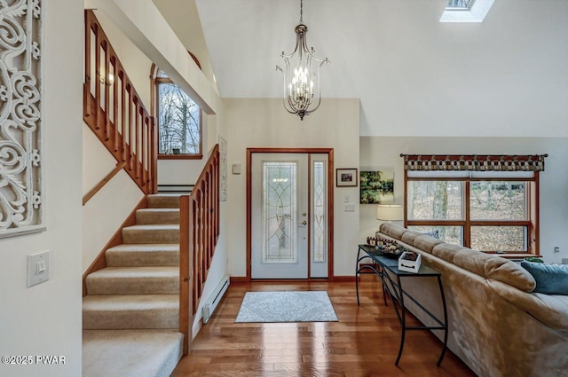 entrance foyer featuring a baseboard heating unit, stairway, a notable chandelier, and a healthy amount of sunlight