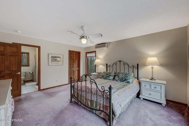 bedroom with light carpet, an AC wall unit, ensuite bath, baseboards, and ceiling fan