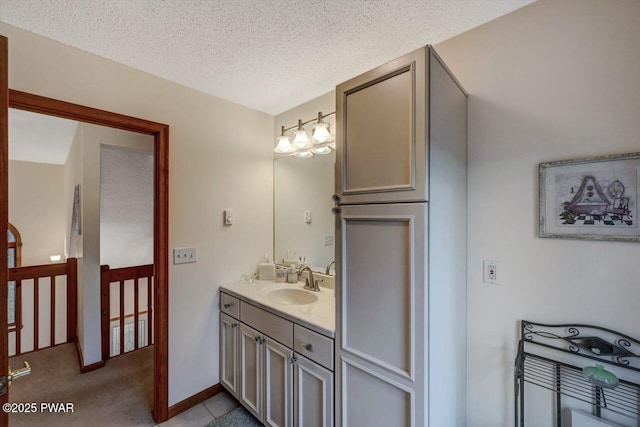 bathroom with baseboards, a textured ceiling, and vanity