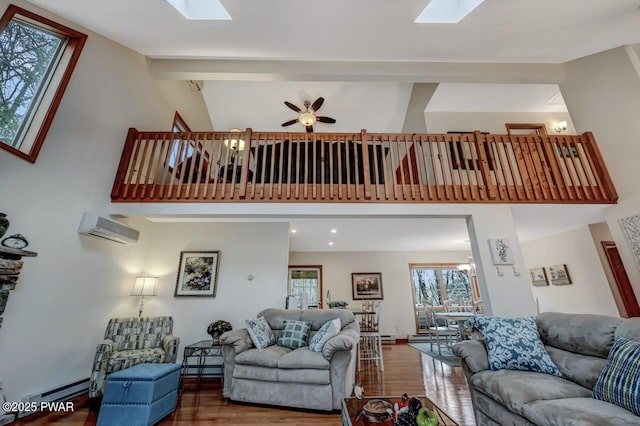 living room featuring wood finished floors, beam ceiling, a skylight, and a wall mounted AC