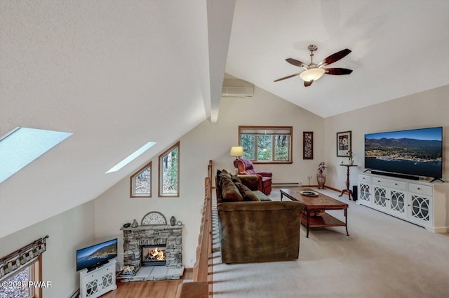 living room with a baseboard radiator, vaulted ceiling with skylight, a fireplace, ceiling fan, and carpet flooring