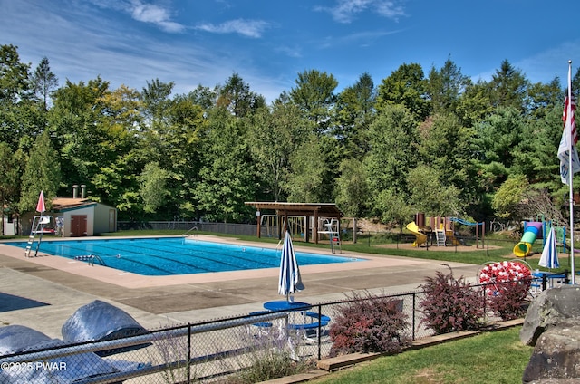 pool with an outbuilding, a shed, fence, playground community, and a patio area