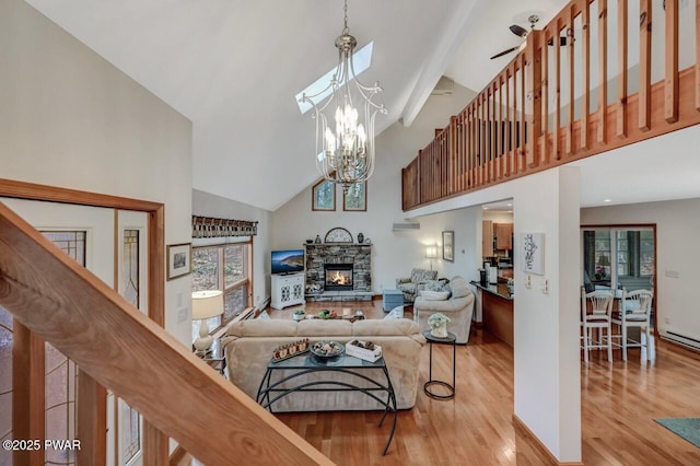 living room featuring light wood finished floors, a stone fireplace, ceiling fan with notable chandelier, and high vaulted ceiling