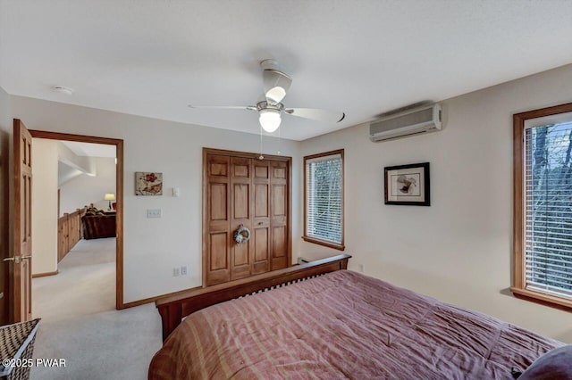 bedroom featuring a wall mounted air conditioner, light carpet, a closet, baseboards, and ceiling fan