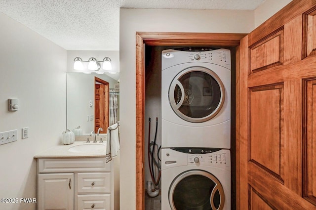 clothes washing area with a textured ceiling, laundry area, stacked washer and dryer, and a sink