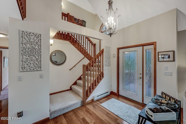 foyer with wood finished floors, an inviting chandelier, a baseboard radiator, baseboards, and stairs