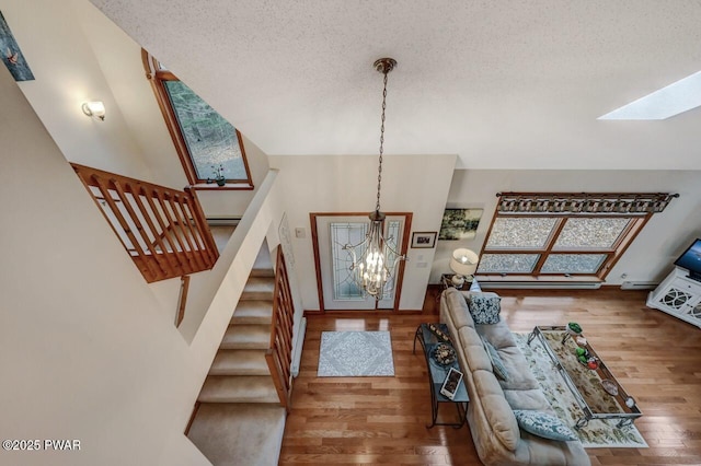 foyer entrance with wood finished floors, an inviting chandelier, a skylight, and stairs