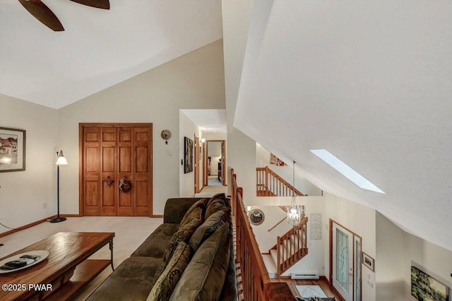 living room with a ceiling fan, stairway, a skylight, carpet flooring, and a baseboard radiator