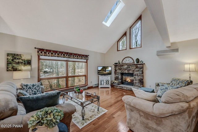 living room featuring high vaulted ceiling, an AC wall unit, wood finished floors, a stone fireplace, and a skylight