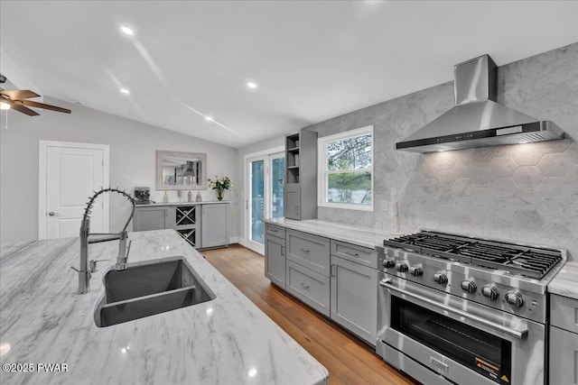 105 Cherry Point Ct, Hawley, PA 18428 - kitchen with high end range, wall chimney exhaust hood, a sink, gray cabinets, and vaulted ceiling