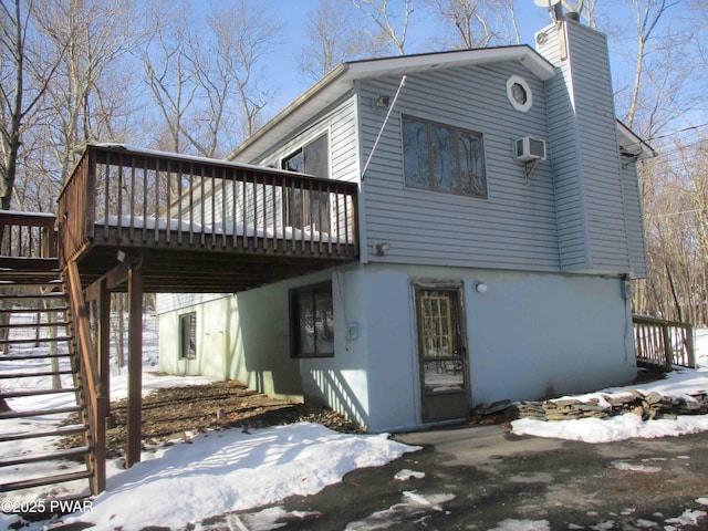 view of snowy exterior featuring a wall unit AC and a wooden deck