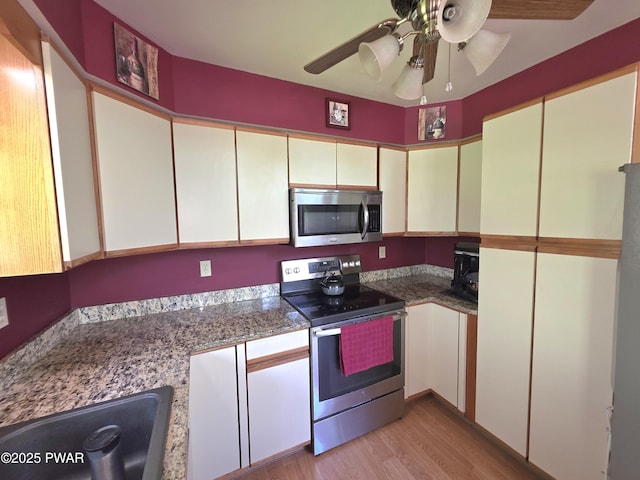 1304 Pratt Hollow Rd, Nicholson, PA 18446 - kitchen with appliances with stainless steel finishes, light wood finished floors, ceiling fan, a sink, and white cabinetry