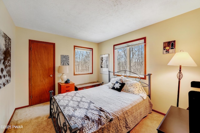 bedroom featuring light colored carpet, a textured ceiling, and baseboards