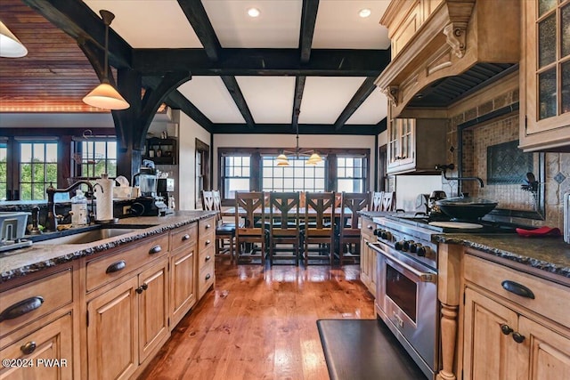 kitchen featuring sink, pendant lighting, high end stainless steel range oven, and light hardwood / wood-style floors