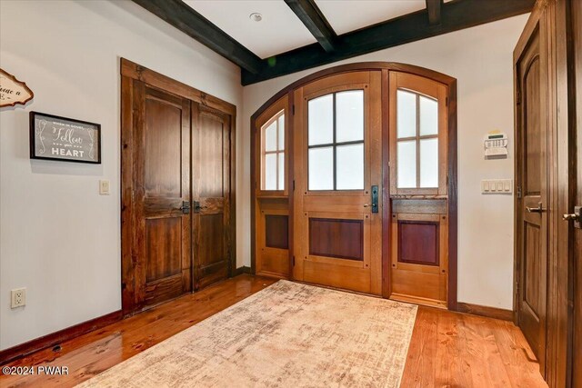 entryway featuring beamed ceiling and light wood-type flooring