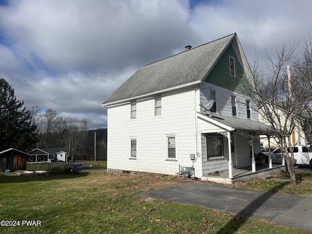 view of property exterior featuring a shingled roof, covered porch, and a lawn